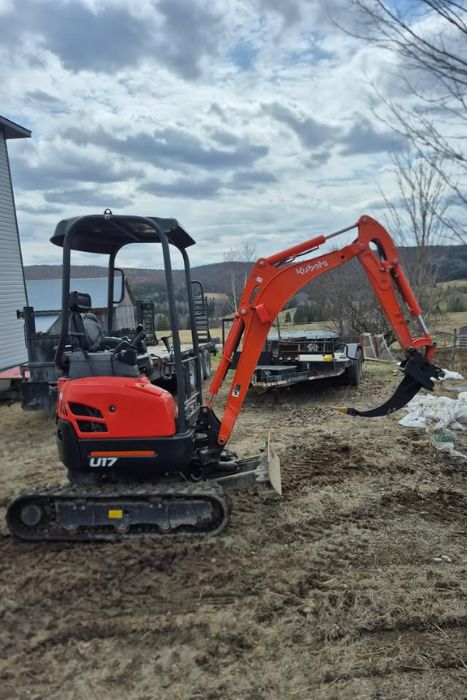Mini-excavatrice Kubota U17 équipée d'une griffe de décapage pour les travaux d'aménagement et de nettoyage de terrain.