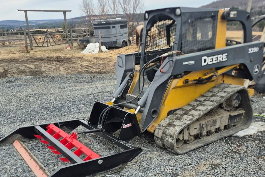 Chargeuse sur chenilles John Deere 329D équipée d'une niveleuse pour des travaux de nivellement de terrain à Saint-Victor.